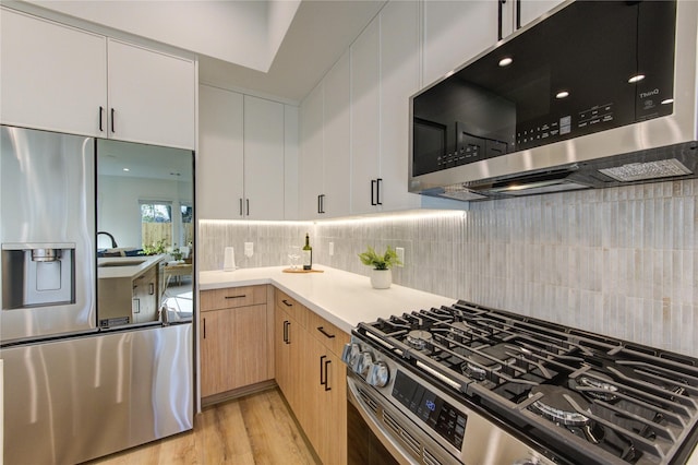 kitchen with light wood finished floors, tasteful backsplash, light countertops, appliances with stainless steel finishes, and light brown cabinets