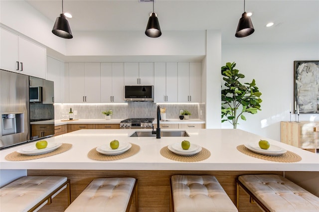 kitchen with light countertops, appliances with stainless steel finishes, a sink, and decorative backsplash