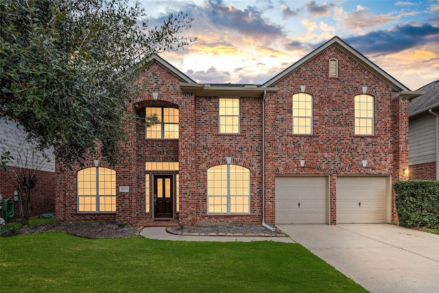 view of front of home with a yard, driveway, brick siding, and an attached garage