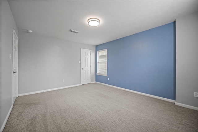 spare room featuring carpet floors, visible vents, and baseboards