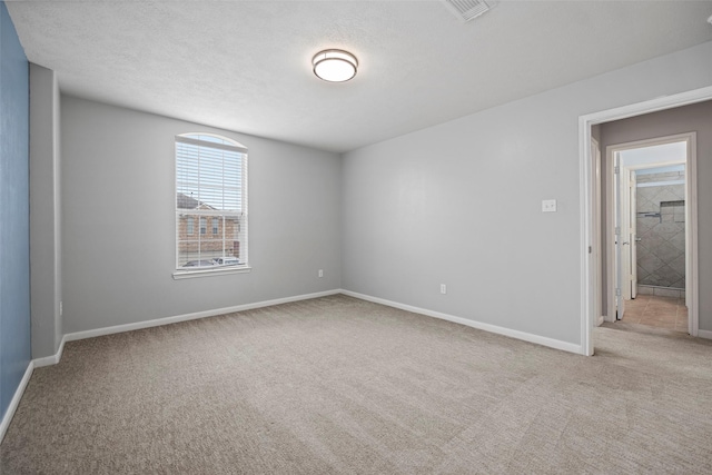 empty room with a textured ceiling, carpet floors, visible vents, and baseboards