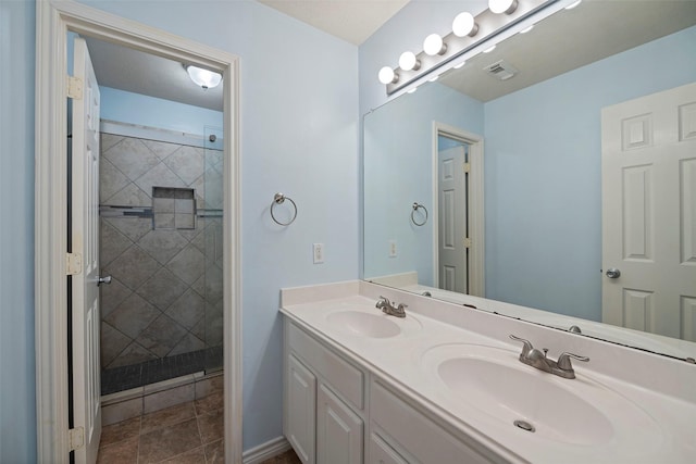 bathroom with double vanity, tiled shower, a sink, and visible vents