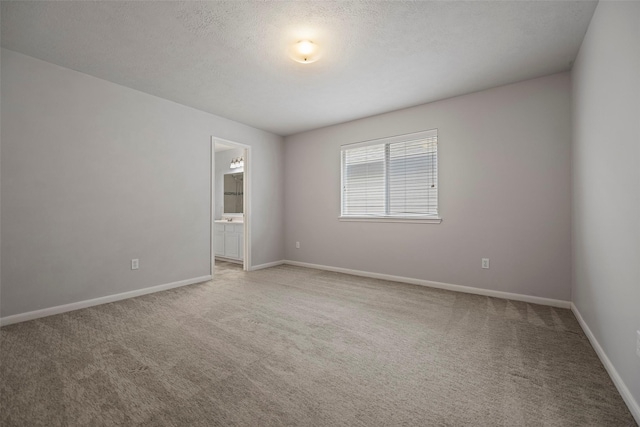 spare room featuring baseboards, a textured ceiling, and light colored carpet