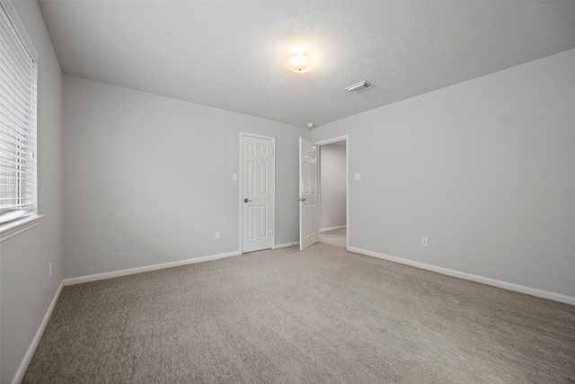 unfurnished room with baseboards, visible vents, and light colored carpet