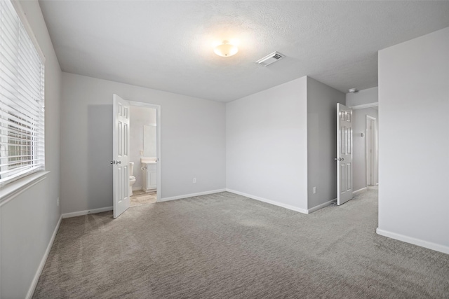 unfurnished bedroom featuring baseboards, visible vents, a textured ceiling, and light colored carpet