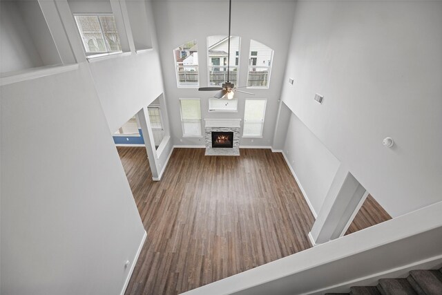 foyer featuring ceiling fan, a high ceiling, a fireplace, wood finished floors, and stairs