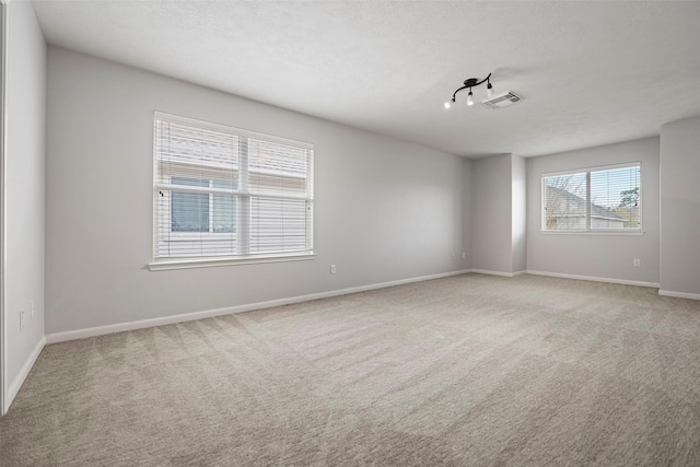 unfurnished room featuring carpet floors, visible vents, a textured ceiling, and baseboards