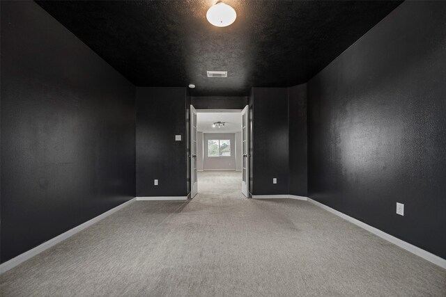 spare room featuring carpet flooring, visible vents, and baseboards