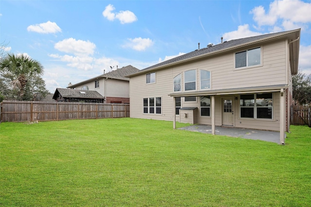 rear view of property featuring a yard, a patio, and a fenced backyard