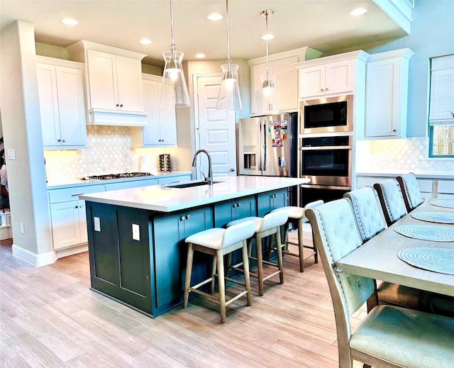 kitchen with a sink, stainless steel appliances, custom exhaust hood, and light wood-style flooring