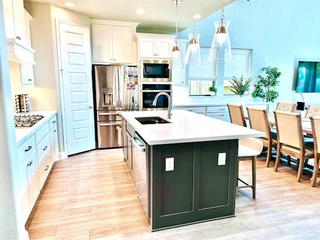 kitchen with stainless steel appliances, light countertops, light wood-style floors, and a sink