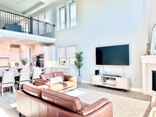 living area featuring a glass covered fireplace, light wood-style flooring, plenty of natural light, and baseboards