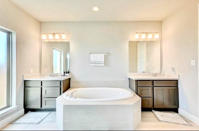 bathroom with a wealth of natural light, two vanities, and a bath