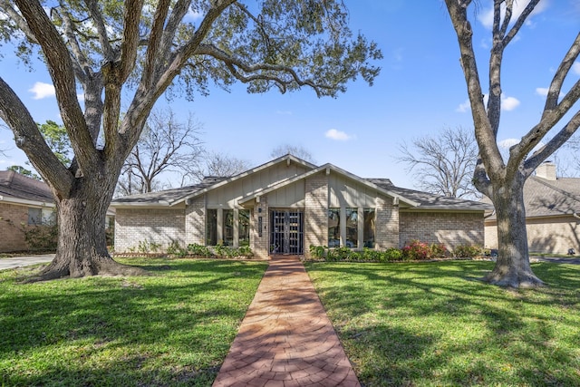 mid-century home with a front yard and brick siding