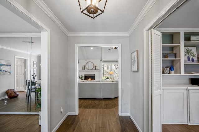 hall with dark wood-style flooring, crown molding, and baseboards