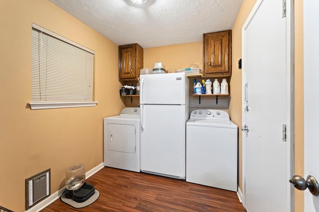 laundry room with dark wood-style flooring, cabinet space, washing machine and dryer, a textured ceiling, and baseboards