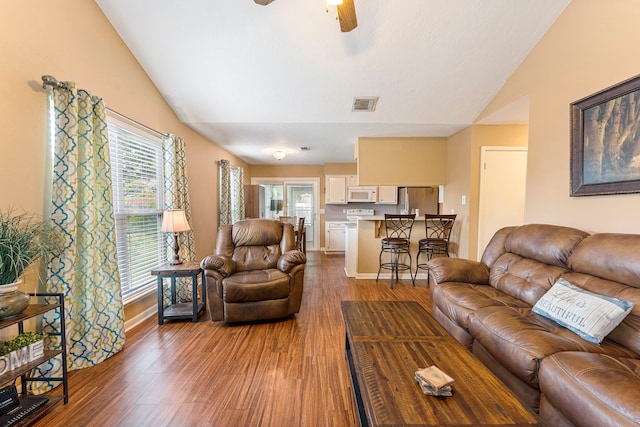 living area featuring lofted ceiling, a wealth of natural light, wood finished floors, and visible vents