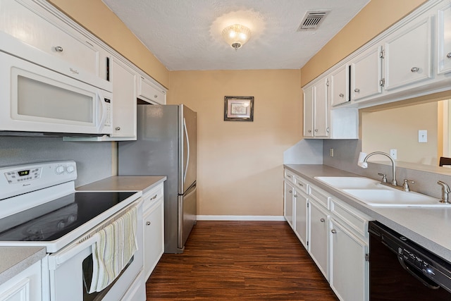 kitchen with white appliances, visible vents, a sink, and white cabinetry