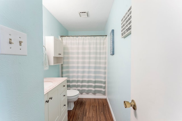 bathroom featuring visible vents, a shower with shower curtain, toilet, wood finished floors, and vanity