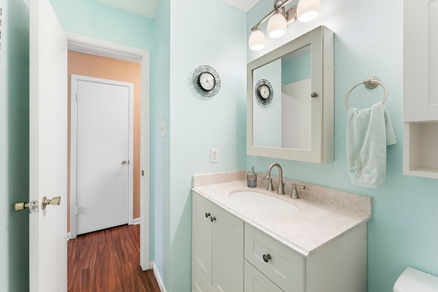 half bathroom featuring toilet, wood finished floors, vanity, and baseboards