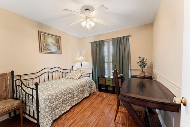 bedroom featuring a wainscoted wall, ceiling fan, and wood finished floors