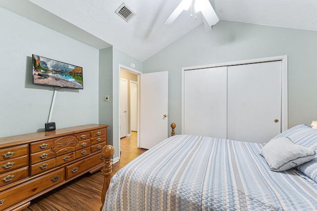 bedroom with visible vents, a ceiling fan, wood finished floors, vaulted ceiling, and a closet