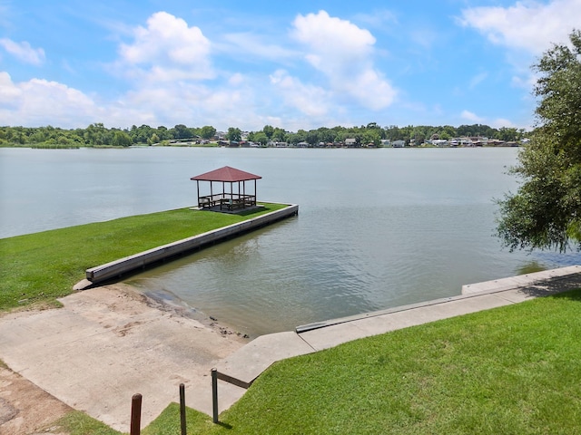 view of dock with a water view, a lawn, and a gazebo