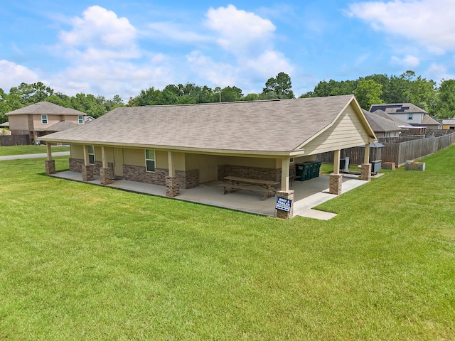 rear view of property with a shingled roof, a lawn, fence, a patio area, and brick siding