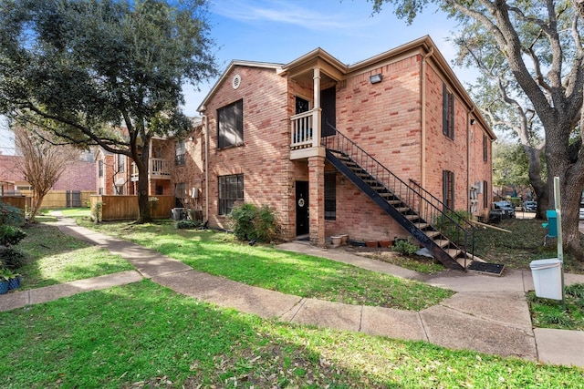 view of front of property with central air condition unit, a front yard, brick siding, and stairs