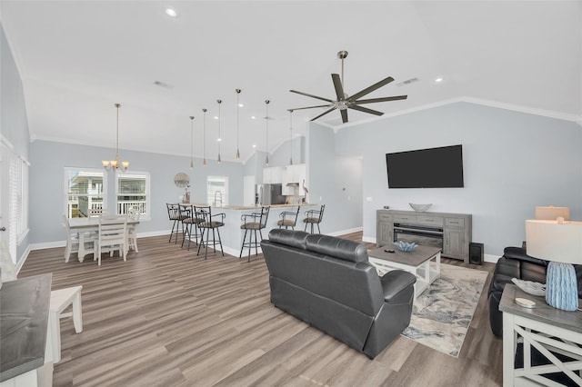 living room with ornamental molding, baseboards, visible vents, and light wood finished floors