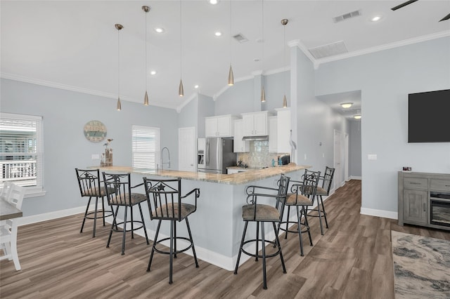 kitchen featuring high vaulted ceiling, ornamental molding, stainless steel refrigerator with ice dispenser, and baseboards