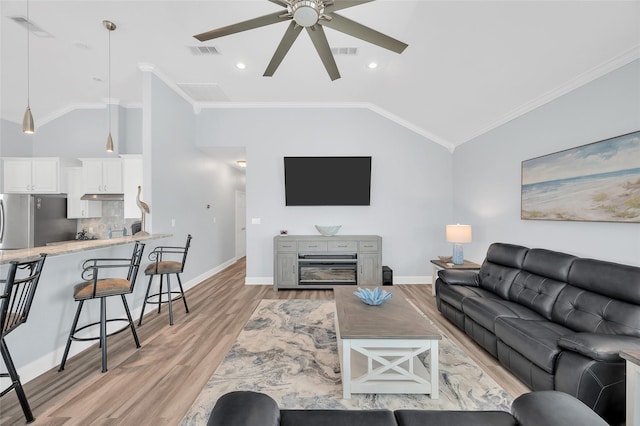 living area featuring light wood-type flooring, visible vents, and crown molding