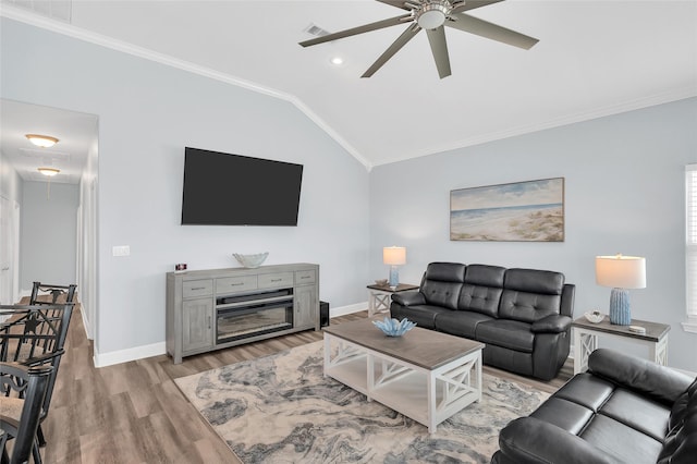 living area featuring lofted ceiling, baseboards, light wood finished floors, attic access, and crown molding