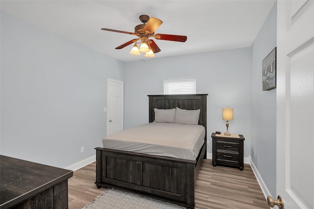 bedroom with a ceiling fan, light wood-style flooring, and baseboards