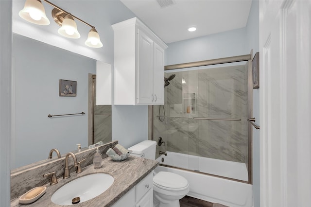 bathroom featuring toilet, shower / bath combination with glass door, visible vents, and vanity