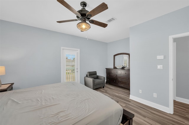 bedroom with wood finished floors, visible vents, and baseboards