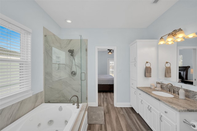 ensuite bathroom with vanity, a shower stall, wood finished floors, a whirlpool tub, and baseboards