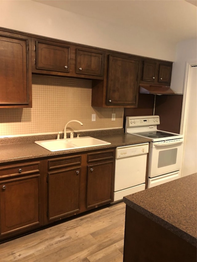 kitchen with decorative backsplash, a sink, dark brown cabinetry, light wood-type flooring, and white appliances