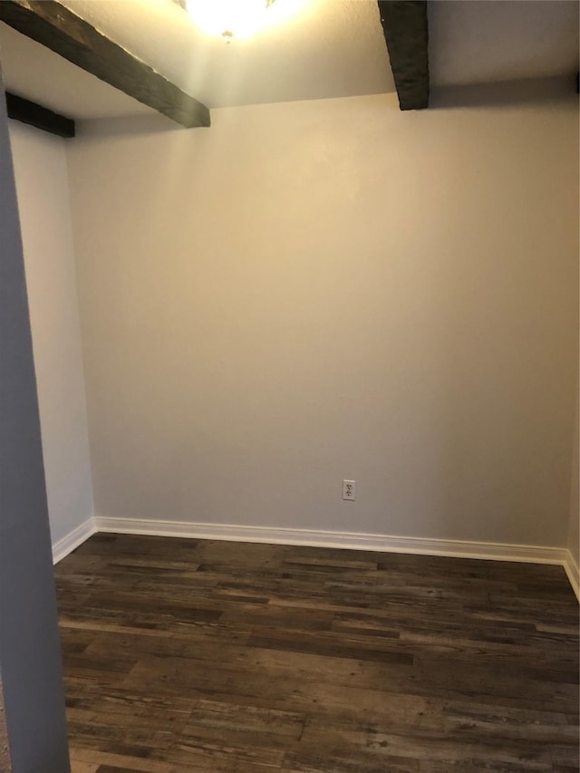 empty room with dark wood-style flooring, beamed ceiling, and baseboards