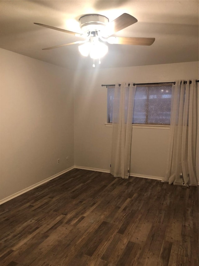 spare room with dark wood finished floors, baseboards, and ceiling fan