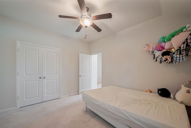 bedroom with a ceiling fan, a closet, light carpet, and baseboards