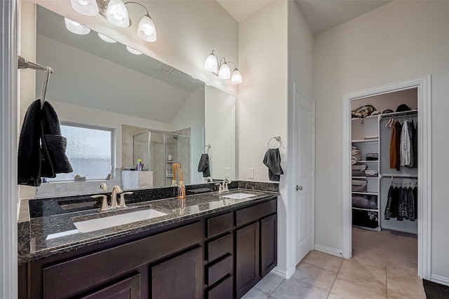 full bath with double vanity, a spacious closet, a sink, a shower stall, and tile patterned flooring