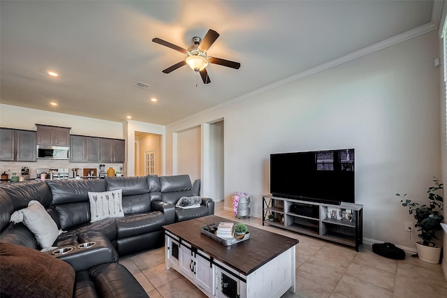 living room featuring light tile patterned floors, visible vents, ornamental molding, a ceiling fan, and baseboards