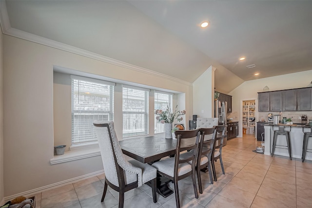 dining area featuring lofted ceiling, light tile patterned floors, baseboards, and crown molding