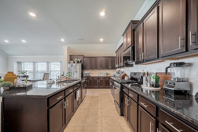 kitchen featuring dark brown cabinetry, dark stone countertops, appliances with stainless steel finishes, and a sink