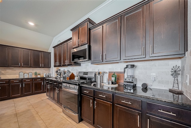 kitchen featuring light tile patterned floors, stainless steel appliances, backsplash, dark brown cabinetry, and dark stone countertops