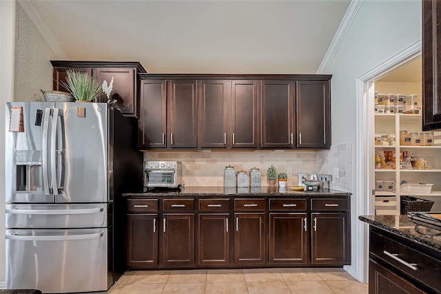 kitchen with stainless steel fridge with ice dispenser, dark stone countertops, dark brown cabinets, crown molding, and backsplash