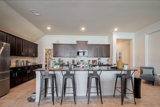 kitchen featuring a breakfast bar area, stainless steel appliances, tasteful backsplash, visible vents, and dark brown cabinetry