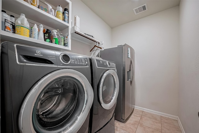 washroom featuring visible vents, washing machine and dryer, light tile patterned flooring, laundry area, and baseboards