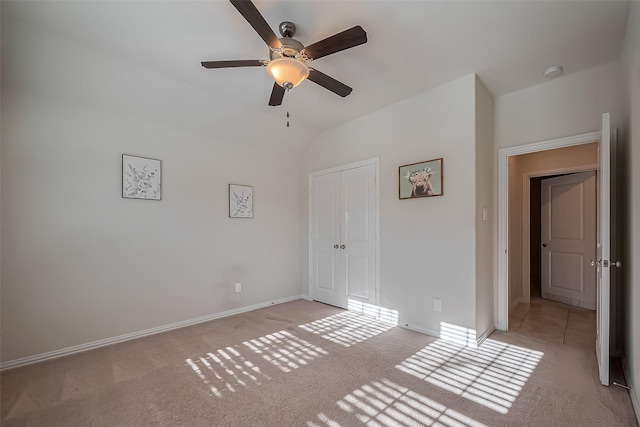 unfurnished bedroom featuring light carpet, ceiling fan, baseboards, and vaulted ceiling